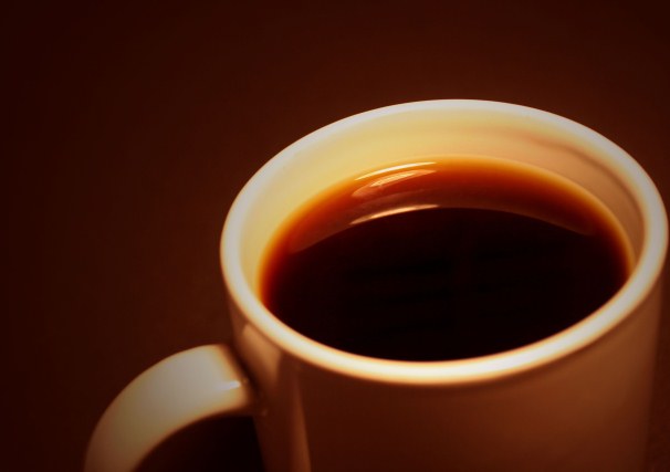 White coffee mug against dark brown background.
